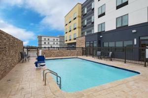 a swimming pool with chairs and a building at Fairfield by Marriott Inn & Suites Waller in Waller