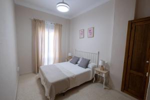 1 dormitorio con cama blanca y ventana en Apartamento America, en Sanlúcar de Barrameda