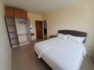 seville suites في إلدوريت: غرفة نوم بسرير ابيض كبير مع مخدات بيضاء