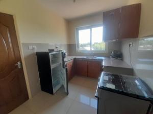 a kitchen with a black refrigerator and a window at seville suites in Eldoret