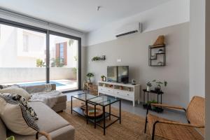 een woonkamer met een bank en een tv bij Villa Flora's 3-Bedroom Retreat with Private Pool in Paralimni