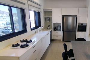 eine Küche mit weißen Schränken und einem Kühlschrank aus Edelstahl in der Unterkunft YalaRent Seasons 4 bedroom apartment with jacuzzi in Eilat