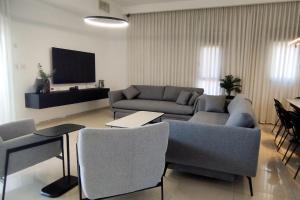 YalaRent Seasons 4 bedroom apartment with jacuzzi في إيلات: غرفة معيشة مع أريكة وتلفزيون