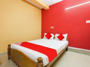 a bedroom with a bed with a red wall at Hotel O Lakshmi Sri Boarding & Lodging in Bengaluru