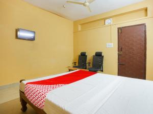 a bedroom with a bed with two chairs and a tv at Hotel O Lakshmi Sri Boarding & Lodging in Bengaluru
