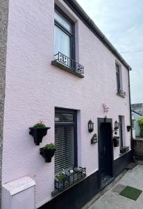 a pink house with two windows and two plants at Beautiful Mumbles/Gower cottage in Swansea