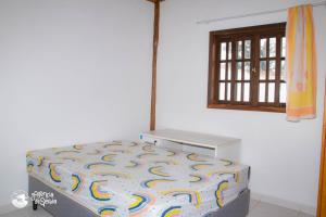 uma pequena cama num quarto com uma janela em Aconchegante casa com piscina e churrasqueira na Praia da Feiticeira em Ilhabela