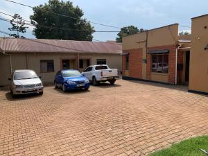 two cars parked in a parking lot next to a building at Pearl suites in Kampala