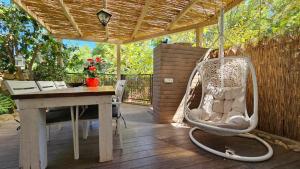 a porch with a swinging chair and a table at Kfar Vradim Hosting in Kefar Weradim