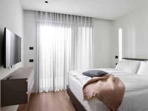 a white bedroom with a bed and a large window at Civico 65 Garda Holiday 19 in Arco