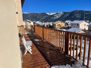 a wooden deck with a chair on a balcony with mountains at Chalet à formiguères de type 4 terrasse in Formiguères