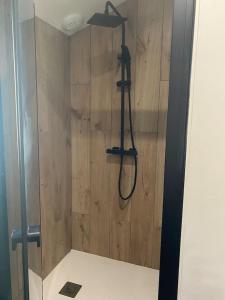 a shower in a bathroom with a wooden wall at Chalet à formiguères de type 4 terrasse in Formiguères