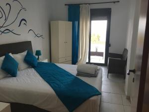 a bedroom with a bed with blue sheets and a window at Petra Mare in Kriopigi