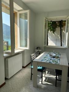 uma sala de jantar com mesa, cadeiras e janelas em Sebino Holiday Home em Monte Isola