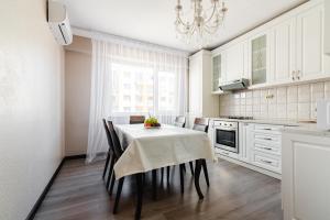 uma cozinha com uma mesa com cadeiras e um lustre em ЖК Теремки em Almaty