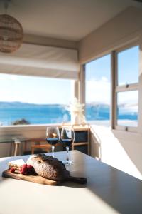 un plato de comida y dos copas de vino en una mesa en Incredible Waterview - 4 Bedroom Hobart Waterside Cottage, en Sandy Bay