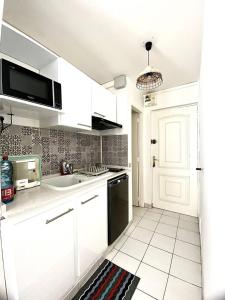 a white kitchen with a sink and a microwave at Apt T1,bien situé Anse Mitan Trois Ilets in Les Trois-Îlets