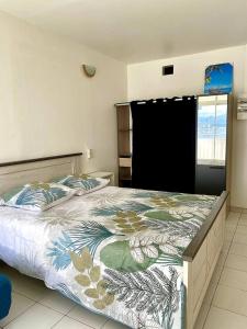um quarto com uma cama grande e um edredão floral em Apt T1,bien situé Anse Mitan Trois Ilets em Les Trois-Îlets