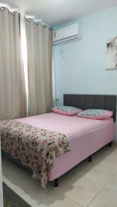 a bedroom with a pink bed with pink sheets and pillows at Calçadão balneário Camboriú in Balneário Camboriú