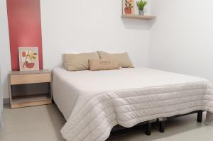 ein Schlafzimmer mit einem weißen Bett und einem Nachttisch in der Unterkunft LA MEJOR ESTADIA EN SANTIAGO DEL ESTERO in Santiago del Estero