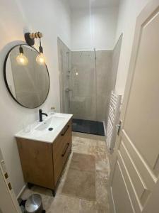 La salle de bains est pourvue d'un lavabo, d'un miroir et d'une douche. dans l'établissement Superbe appartement à 5 minutes à pied de la mer, à Toulon