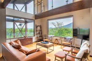 a living room with a couch and a tv and large windows at SANGA HOUSE in Kutchan