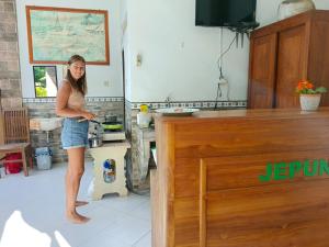 Una donna in piedi in una cucina che prepara il cibo di Jepun Inn a Padangbai