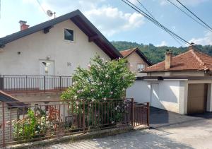 una casa con una valla y un árbol delante de ella en Apartmani BA, en Sarajevo
