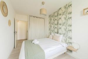a bedroom with a white bed with a tropical wallpaper at Disneyland Appartement in Montévrain