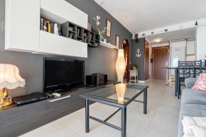 a living room with a tv and a table at Residencial Los Pelicanos in Hospitalet de l'Infant