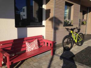 Un banco rojo y una bicicleta aparcada junto a una casa. en Ferienwohnung Manu, en Kisslegg 1 foto más