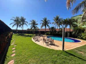 a backyard with a pool and chairs and palm trees at Premier Garden Hotel in José Bonifácio