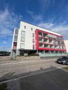 um edifício branco e vermelho com um carro estacionado na frente em Cozy studio in Vantaa, Near Airport with Parking em Vantaa