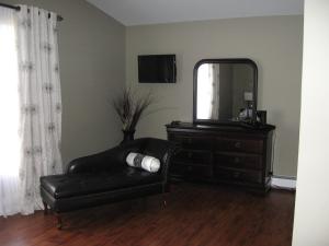 um quarto com uma cadeira, um espelho e uma cómoda em Driftwood Heights B&B em Summerside