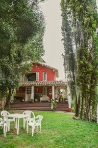 une maison rouge avec des tables et des chaises blanches devant elle dans l'établissement Cabaña típica Boyacense! con vista al lago y chimenea, à Paipa