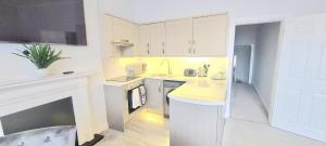 uma cozinha com armários brancos e uma lareira em 3 bed flat 15 min walk from the sea with parking em Bournemouth
