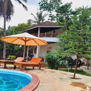 uma piscina com guarda-sol e cadeiras ao lado de uma casa em Manuastro Breeze Villa - Diani Beach em Galu