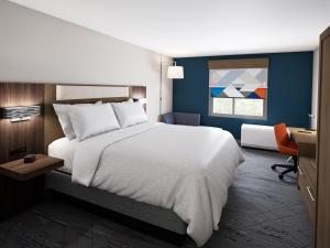 Holiday Inn Express & Suites Ormond Beach - North Daytona, an IHG Hotel في شاطئ أورموند: غرفة نوم مع سرير أبيض كبير ومكتب