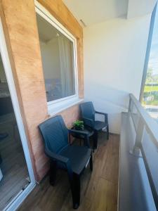 - deux chaises et une table dans une chambre avec fenêtre dans l'établissement Apartmani borova 2, à Veliko Gradište
