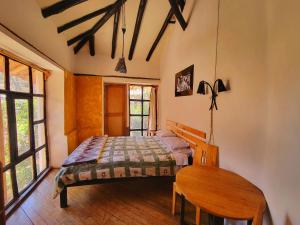 1 dormitorio con cama y mesa de madera en Logde Casa de campo & Retreat Center, en Urubamba
