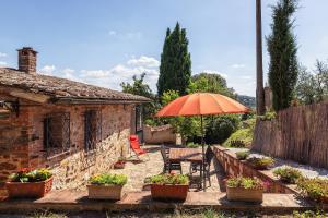 eine Terrasse mit einem orangenen Sonnenschirm, Stühlen und einem Tisch in der Unterkunft CasaMoira in Trequanda