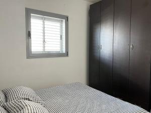 um quarto com uma cama e uma janela em Costa residence em Ashdod