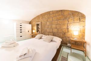 a bedroom with a large white bed and a brick wall at Santa Maria degli Angeli Apartment in Naples
