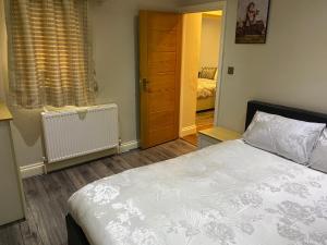 1 dormitorio con cama, ventana y puerta en Ruislip Guest House, en Ruislip