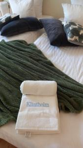 a bed with a green blanket and a book on it at Klintholm Bed & Breakfast & Bistro in Borre