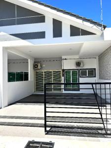 une maison blanche avec un banc devant elle dans l'établissement Zh homestay teluk batik, à Lumut