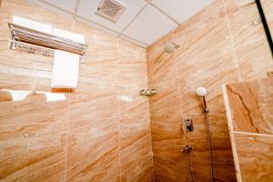 y baño con ducha y pared de madera. en Casa Hotel & Suites, Gachibowli, Hyderabad en Hyderabad