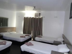 um quarto com três camas e uma janela em Parkway Motel em Queanbeyan