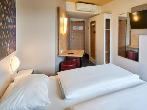 フランクフルト・アム・マインにあるB&B Hotel Frankfurt-Nordのベッドとデスクが備わるホテルルームです。