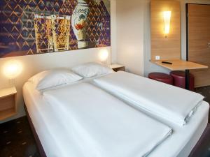 Un pat sau paturi într-o cameră la B&B Hotel Frankfurt-Nord